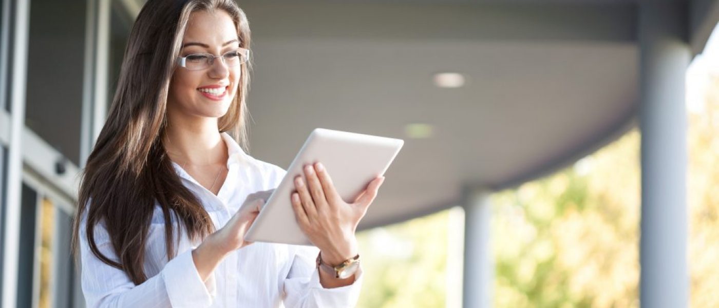 Smiling businesswoman using electronic tablet outside